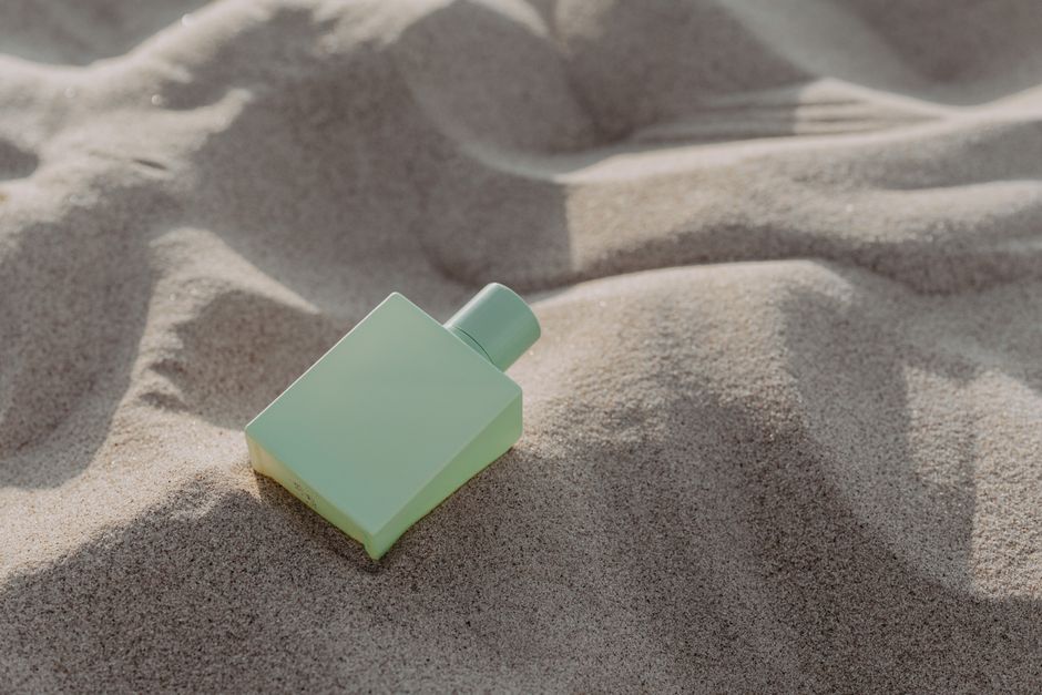 Glass cologne bottle resting on sand