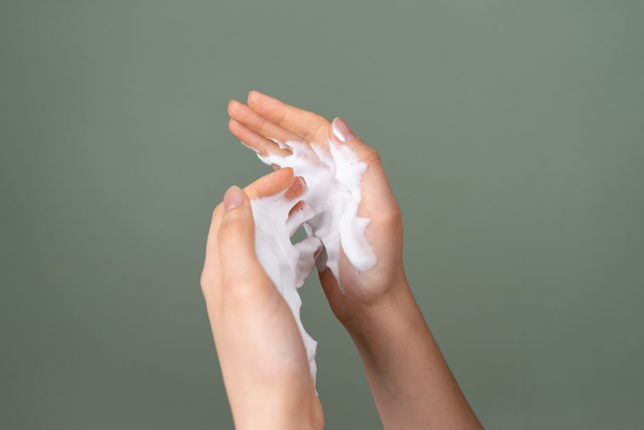 Hands holding a palmful of white face cream