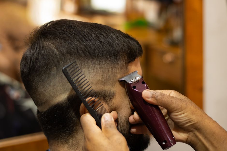 Barber using clippers and comb to give a precise haircut in a barber shop.