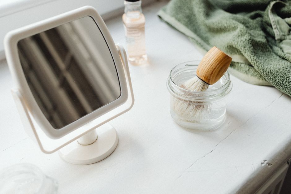 Simple and elegant vanity setup with mirror and shaving brush in minimal design.