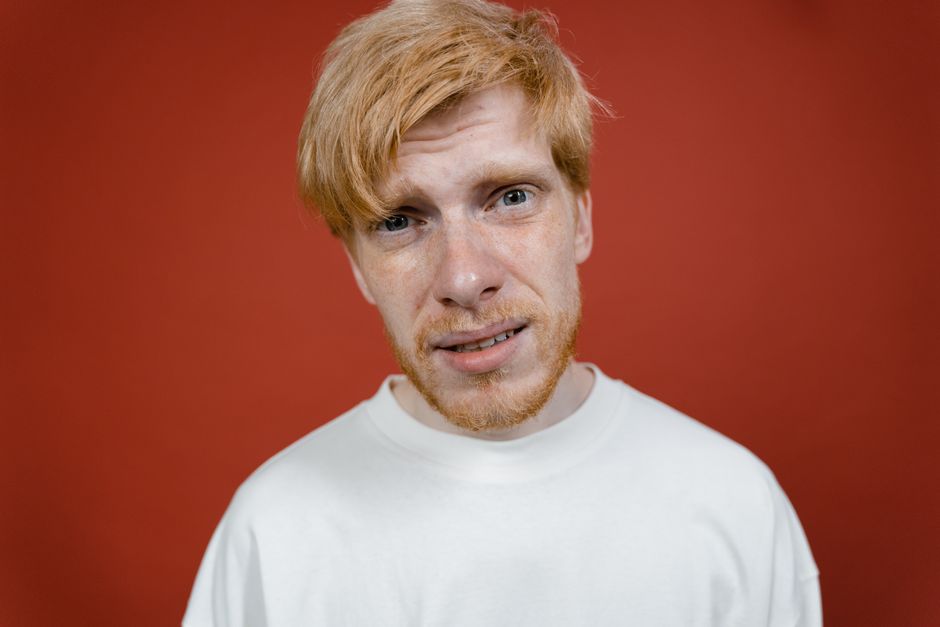 Portrait of a blonde man with beard against red background in a studio.