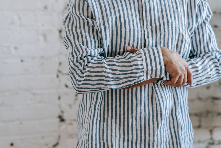 Man buttoning a striped dress shirt