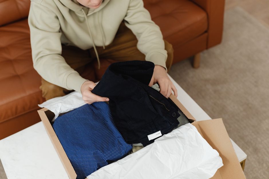 Man folding shirts and knitwear into a box