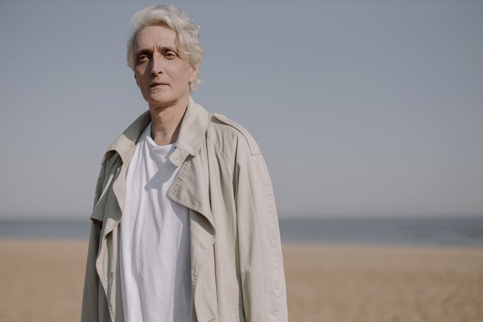 Man in a beige trench coat standing outdoors