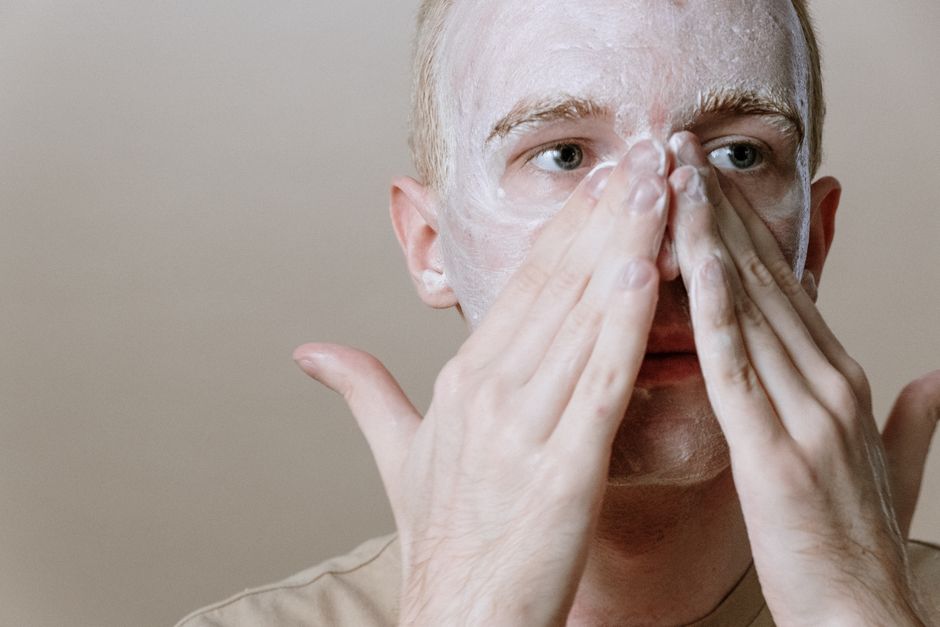 Man rubbing cleanser across his cheeks with both hands