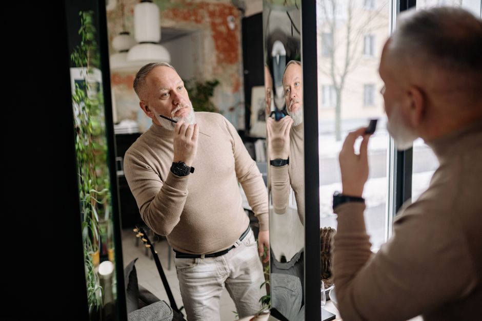 Man touching his chin while looking in a mirror