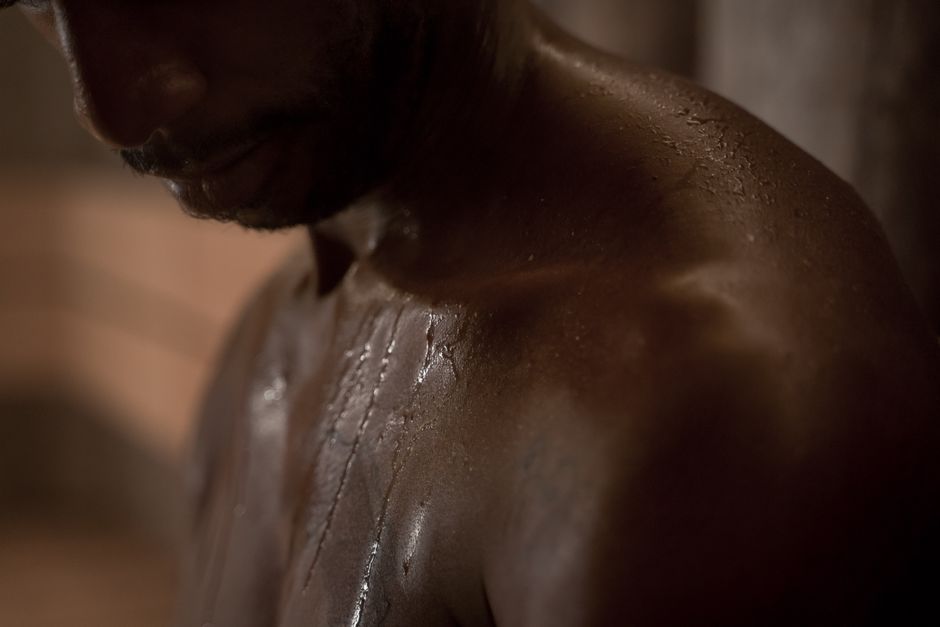 Moody close-up of a man's shoulder with water droplets, capturing texture in low light.