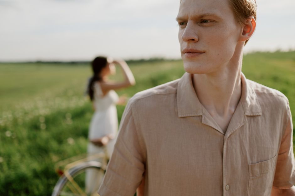 Young couple in a meadow on a summer day, with a bike and lush green field.