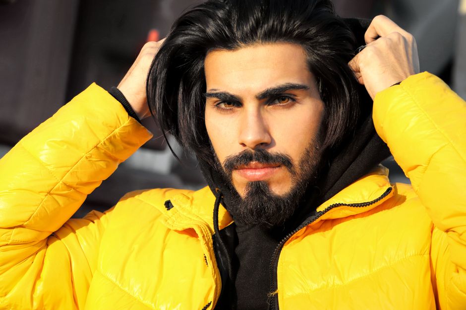 Close-up portrait of a man adjusting his yellow jacket with confidence.